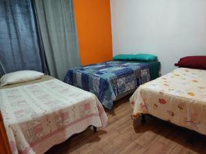 a room with three beds in a room at Hostal Las Armonías 3 in Panajachel