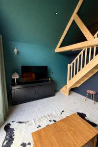 a living room with a large television and a staircase at Chalet in Paluel