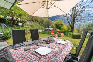a table with an umbrella and some chairs at Vallemaggia Green House in Sornico