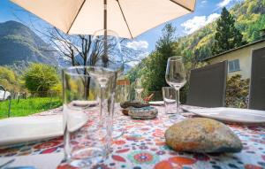 a table with glasses and rocks on a table with an umbrella at Vallemaggia Green House in Sornico