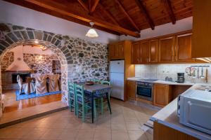 a kitchen with a table and a stone wall at Kamara House in Tyros