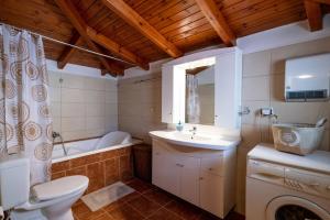 a bathroom with a sink and a toilet and a tub at Kamara House in Tyros +23 photos
