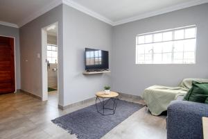a living room with a couch and a tv on a wall at Scheunberg 4 Modern 1 Bedroom Flat in Centurion