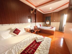 a hotel room with two beds and a desk at Mimosa 2 Hotel - Phan Rang in Phan Rang–Tháp Chàm +3 photos