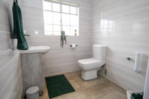 a white bathroom with a toilet and a sink at Scheunberg 4 Modern 1 Bedroom Flat in Centurion