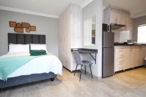 a bedroom with a bed and a desk and a kitchen at Scheunberg 4 Modern 1 Bedroom Flat in Centurion