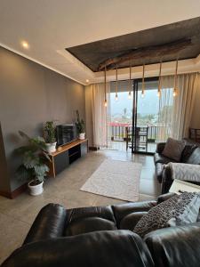 a living room with leather couches and a balcony at The Concrete Edit in Benoni