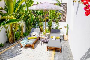 a patio with two lounge chairs and an umbrella at White Memories boutique home - Romantic Stay in Afandou in Afantou