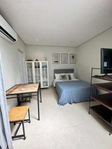 a bedroom with a bed and a table and a television at Studio Matriz 1 e 2 in São Sebastião