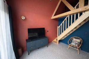 a living room with a staircase and a television at Tiny Chalet in Paluel