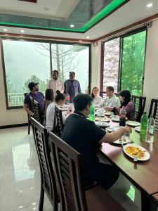 a group of people sitting at a table eating food at Nathia Gali Relax Inn Hotel in Naka