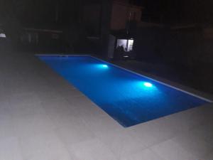 a blue swimming pool with lights in a dark room at Departamentos Algarrobo in Arroyo de Los Patos