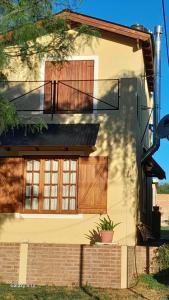 a house with wooden doors and a balcony at Departamentos Algarrobo in Arroyo de Los Patos