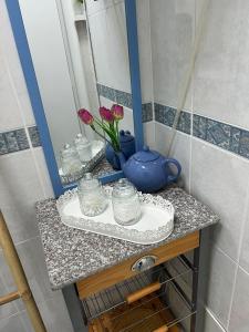 a bathroom counter with a blue pot and flowers in a mirror at Camurichico in Figueira da Foz +10 photos
