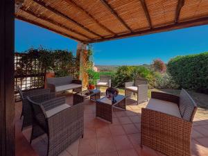 a patio with wicker chairs and tables under a pergola at Villa Gilda - Private Pool by Host Hero in Stintino