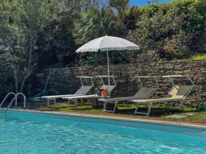 a pool with two lounge chairs and an umbrella next to a swimming pool at Villa Gilda - Private Pool by Host Hero in Stintino