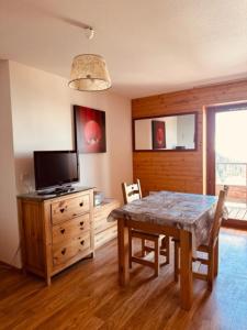 a dining room with a table and a television at studio Nivéole 303 in Chamrousse