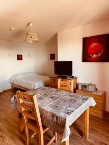 a bedroom with a table and a bed and a television at studio Nivéole 303 in Chamrousse