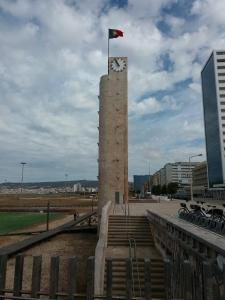 a clock tower with a flag on top of it at Camurichico in Figueira da Foz