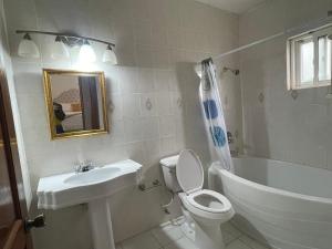 a white bathroom with a sink and a toilet and a tub at Bright Bay Garden Suite in Montego Bay +7 photos
