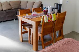 a wooden dining room table with chairs and a couch at Kitnet confortável in Foz do Iguaçu +12 photos