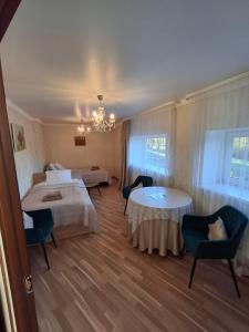 a hotel room with two beds and a table and chairs at Apartmenti Ezerkrasti in Jaunpils