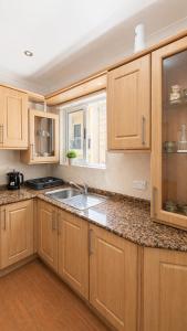 a kitchen with wooden cabinets and a sink at Calypso 3 Large Stylish Apartment in Paceville with Mercury Tower View Ideal for Groups in St. Julianʼs +19 photos