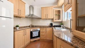 a kitchen with wooden cabinets and granite counter tops at Calypso 3 Large Stylish Apartment in Paceville with Mercury Tower View Ideal for Groups in St. Julianʼs