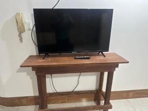 a television on a wooden table with a remote control at Departamento con parqueadero céntrico in Baños