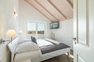 a white bedroom with a bed and a window at Ferienhaus Rotschenkel in Dagebüll