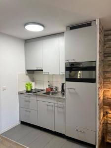 a kitchen with white cabinets and a stainless steel refrigerator at Rawda Ferien Wohnung 2 in Interlaken