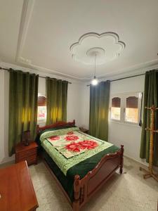 a bedroom with a bed with red flowers on it at Appartement Ajdir in Al Hoceïma