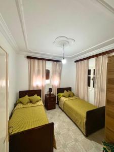 a bedroom with two beds with yellow sheets at Appartement Ajdir in Al Hoceïma