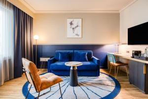 a hotel room with a blue couch and a table at voco Gent by IHG in Ghent