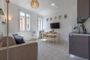 a living room with a couch and a kitchen and a table at NURAS - Casa Aurelia square view old town in Alghero
