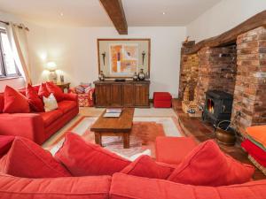 a living room with red furniture and a brick fireplace at The Haybarn in Lichfield