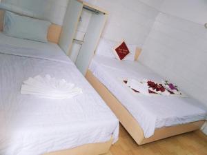 two beds in a small room with a box of roses at Mimosa 6 Hotel - Phan Rang in Phan Rang–Tháp Chàm