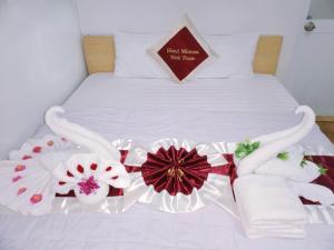 a bed with white sheets and flowers on it at Mimosa 6 Hotel - Phan Rang in Phan Rang–Tháp Chàm