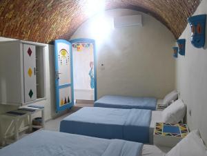 a room with two beds and a painting on the wall at malindy KA nubian houseماليندى كا in Aswan +185 photos