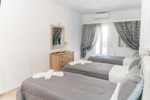 a bedroom with three beds and a mirror at Hotel Lodos in Karterados