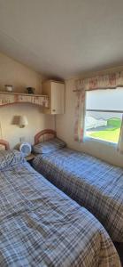 a bedroom with two beds and a window with a view at The salsbury lyons robin hood park,rhyl in Meliden