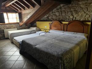 two beds in a room with a stone wall at La Venta de Quijas in Quijas +39 photos
