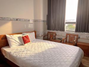 a bedroom with a bed and two chairs and a window at Mimosa 7 Hotel - Phan Rang in Phan Rang–Tháp Chàm