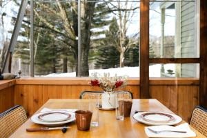 a wooden table with plates and a vase of flowers at Maison Hôte in Magog-Orford