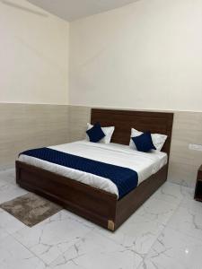 a bedroom with a large bed with blue pillows at Hotel Gold in Faridabad +4 photos