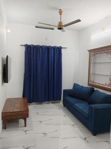 a living room with a blue couch and a ceiling fan at Aditi Residency in Cochin