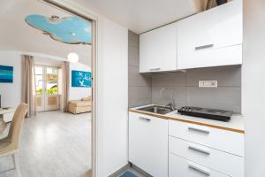 a kitchen with white cabinets and a sink at My Suite Sorrento in Sorrento
