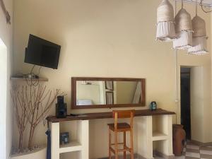a mirror on a wall with a desk with a chair at Takasira Appart Hôtel Downtown in Fort Dauphin +5 photos