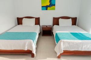 two beds sitting next to each other in a room at Sanha Plus Hotel in Santa Marta