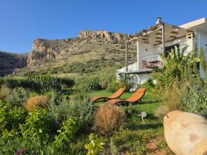 a house with two chairs and a mountain in the background at Casa di Olive Luxury Secluded Sea View Villa in South Crete in Goúdhouros